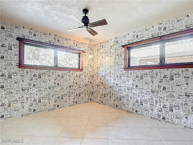 spare room with ceiling fan and light tile patterned flooring