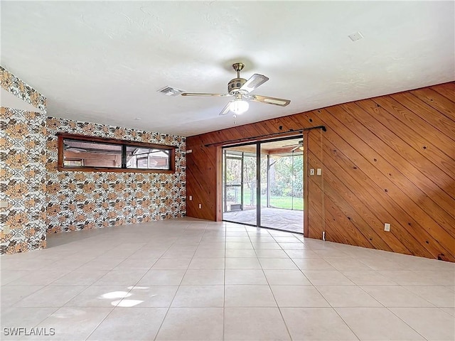 spare room featuring wood walls, ceiling fan, and light tile patterned flooring