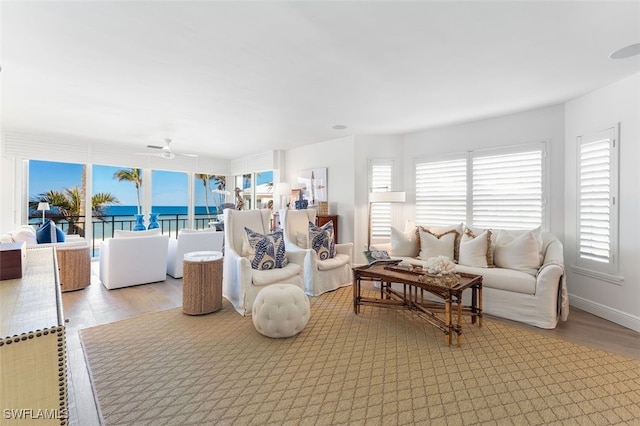 living room featuring ceiling fan, a water view, and light hardwood / wood-style flooring