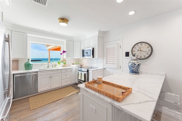 kitchen featuring white cabinets, stainless steel appliances, sink, kitchen peninsula, and light stone counters