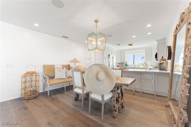 dining room with sink, an inviting chandelier, and wood-type flooring