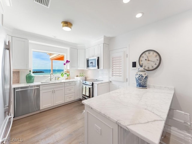 2401 Gulf Shore Blvd N Unit 2, Naples, FL 34103 - kitchen featuring appliances with stainless steel finishes, sink, light wood-type flooring, white cabinetry, and kitchen peninsula