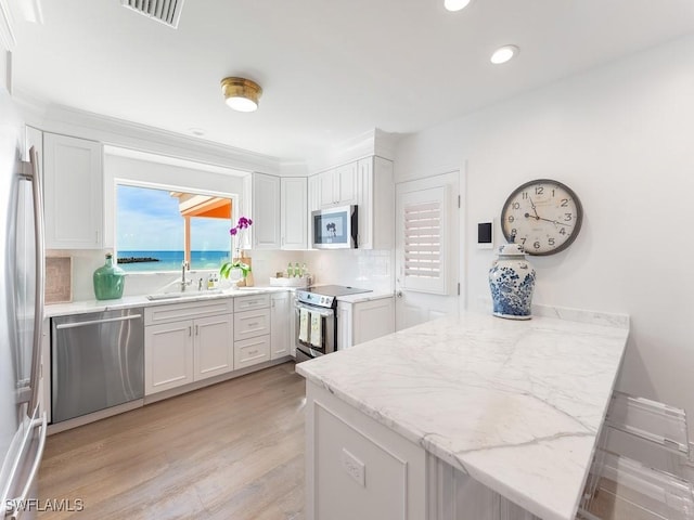 kitchen featuring appliances with stainless steel finishes, sink, light wood-type flooring, white cabinetry, and kitchen peninsula