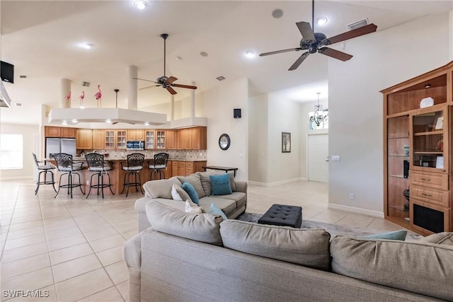 living room featuring ceiling fan with notable chandelier, light tile patterned floors, and high vaulted ceiling