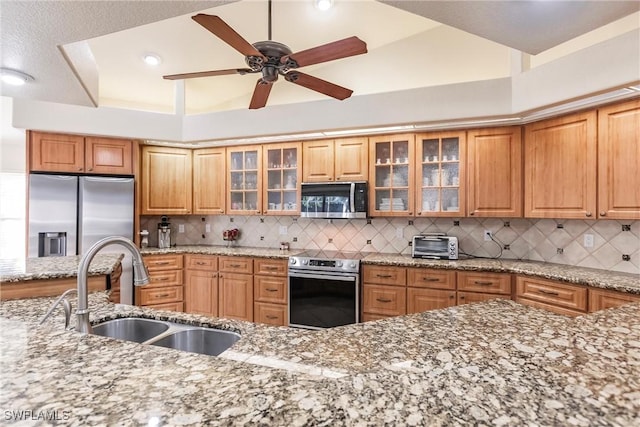 kitchen with tasteful backsplash, appliances with stainless steel finishes, sink, and light stone counters