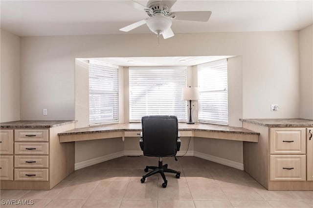 tiled office space with built in desk and ceiling fan