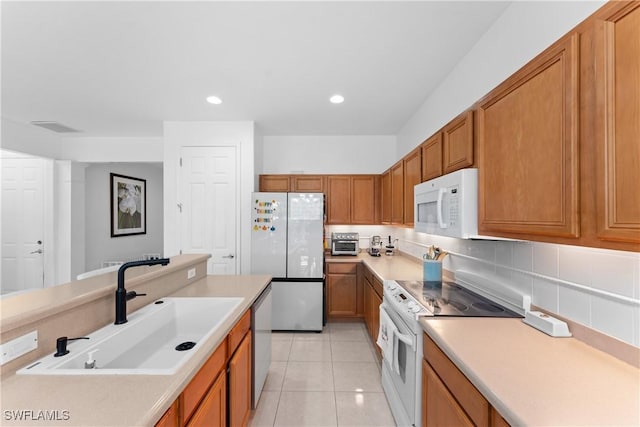 kitchen with decorative backsplash, light tile patterned flooring, white appliances, and sink