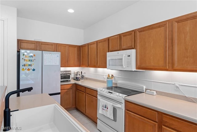 kitchen featuring sink, light tile patterned flooring, and white appliances