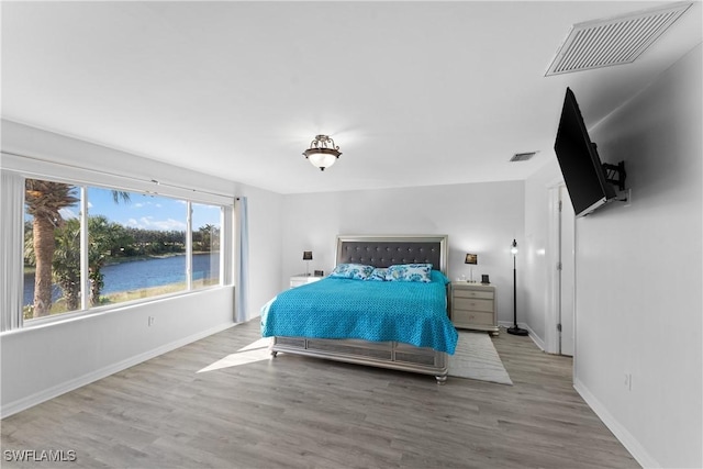 bedroom featuring a water view and light hardwood / wood-style floors