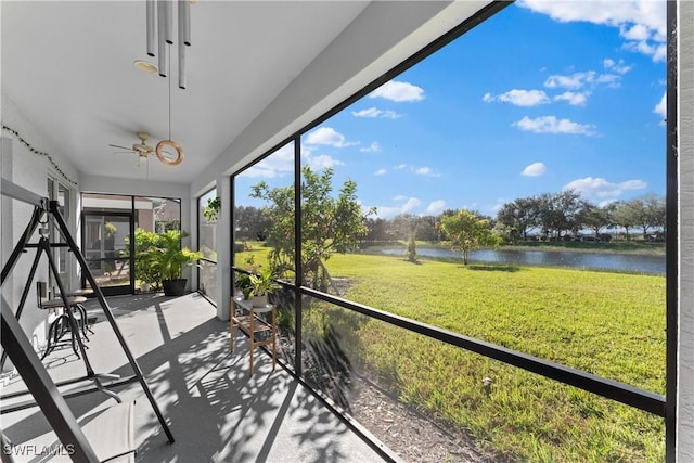 unfurnished sunroom with ceiling fan and a water view