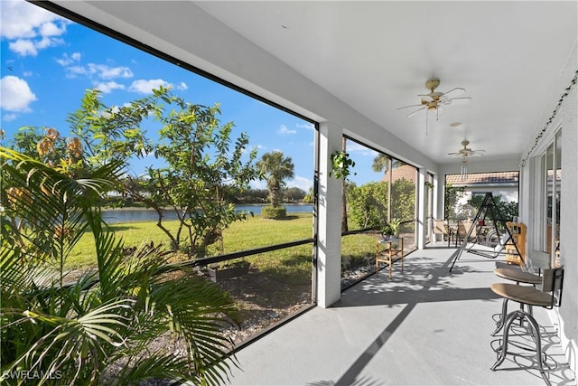 sunroom featuring a water view and ceiling fan