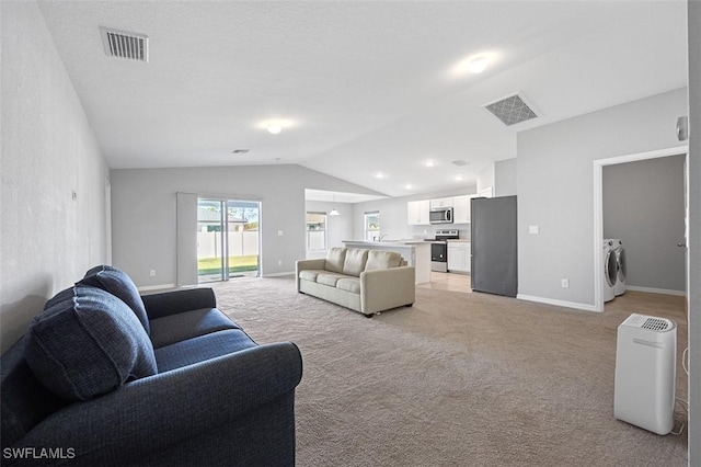 carpeted living room with washing machine and dryer and vaulted ceiling