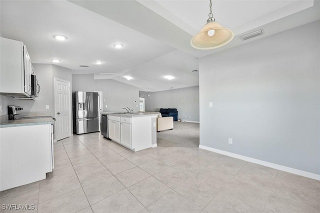 kitchen with white cabinetry, lofted ceiling, decorative light fixtures, a kitchen island with sink, and appliances with stainless steel finishes