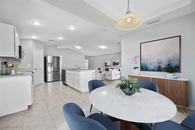 dining room featuring sink, light tile patterned flooring, and lofted ceiling