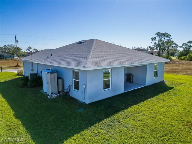 rear view of house with central AC unit and a lawn