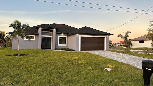 prairie-style home featuring a garage and a lawn