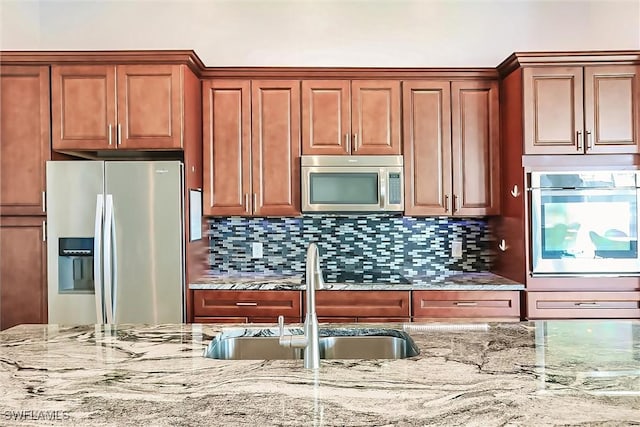 kitchen featuring light stone countertops, decorative backsplash, sink, and stainless steel appliances