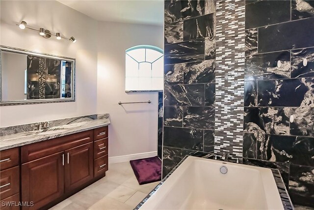 bathroom with vanity, a bathtub, and tile walls