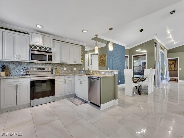 kitchen featuring kitchen peninsula, pendant lighting, decorative backsplash, appliances with stainless steel finishes, and ornamental molding