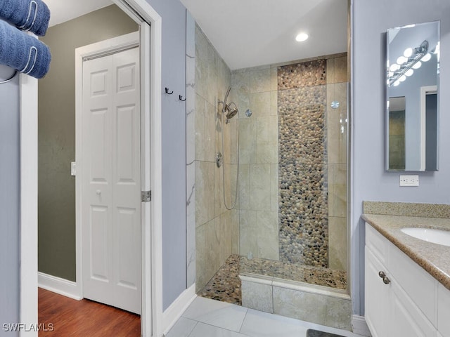 bathroom featuring vanity, wood-type flooring, and tiled shower