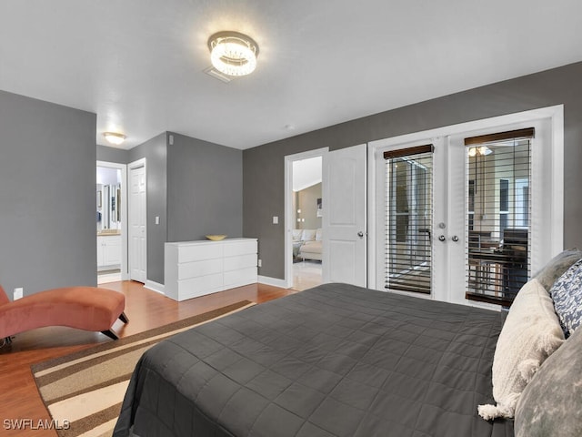 bedroom with access to exterior, french doors, hardwood / wood-style flooring, and ensuite bath