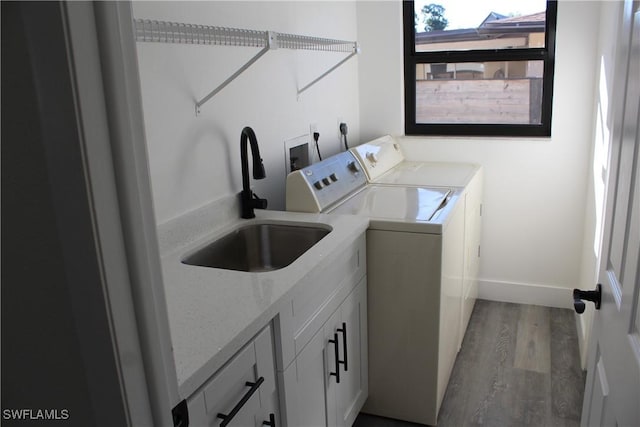 laundry area with cabinets, washing machine and dryer, light hardwood / wood-style flooring, and sink