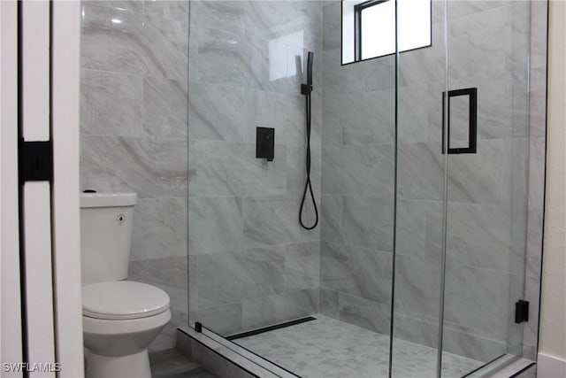 bathroom featuring toilet and a shower with shower door