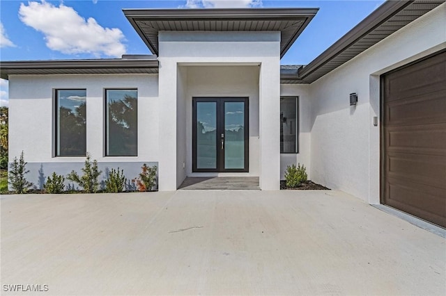 entrance to property featuring a garage, a patio area, and french doors