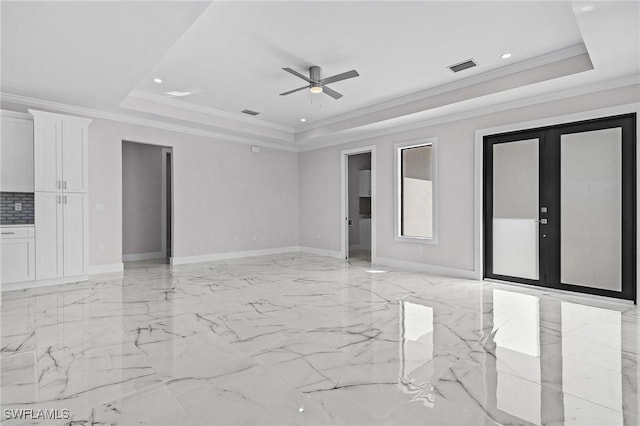 unfurnished room with a raised ceiling, ornamental molding, ceiling fan, and french doors