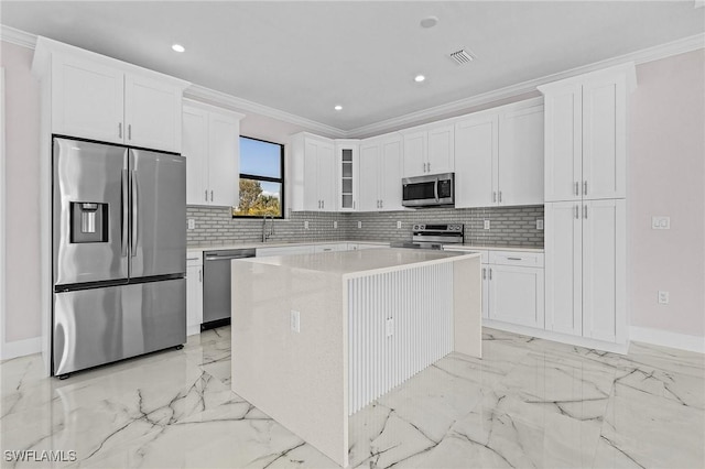 kitchen with white cabinetry, ornamental molding, appliances with stainless steel finishes, and a center island