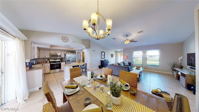 dining space featuring ceiling fan with notable chandelier, lofted ceiling, and light tile patterned flooring