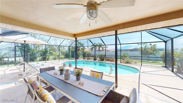 view of pool with glass enclosure, ceiling fan, and a patio area