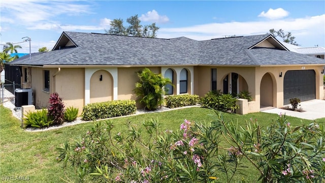 view of front of property with central AC, a front lawn, and a garage