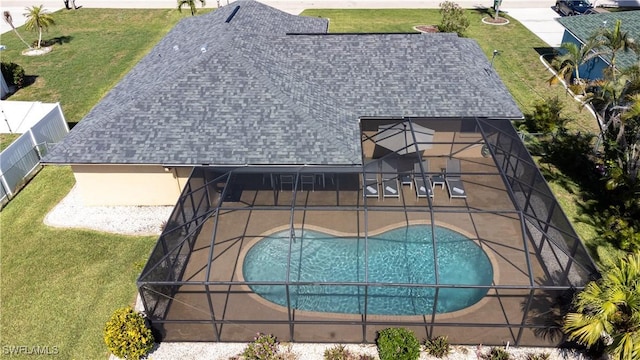 view of pool with glass enclosure, a yard, and a patio