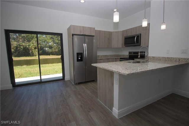 kitchen featuring light stone countertops, appliances with stainless steel finishes, kitchen peninsula, dark wood-type flooring, and pendant lighting