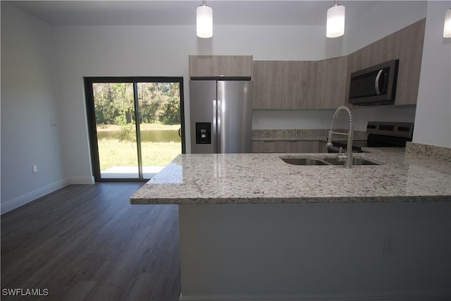 kitchen with light stone countertops, appliances with stainless steel finishes, dark hardwood / wood-style flooring, and pendant lighting