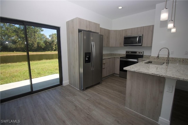 kitchen with sink, hanging light fixtures, light stone countertops, plenty of natural light, and stainless steel appliances