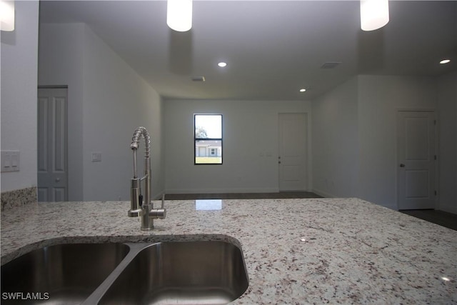 kitchen featuring light stone counters and sink