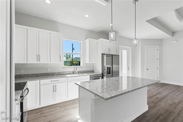 kitchen featuring sink, decorative light fixtures, a center island, stainless steel appliances, and white cabinets