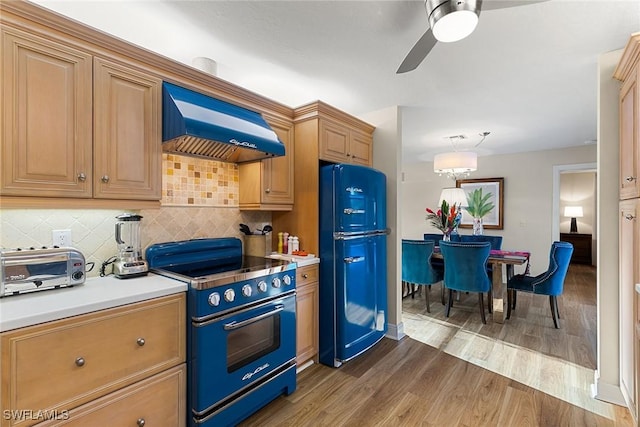 kitchen featuring premium range hood, black refrigerator, hardwood / wood-style flooring, high quality range, and tasteful backsplash