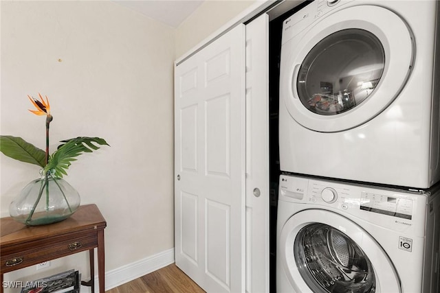 clothes washing area with wood-type flooring and stacked washer and dryer