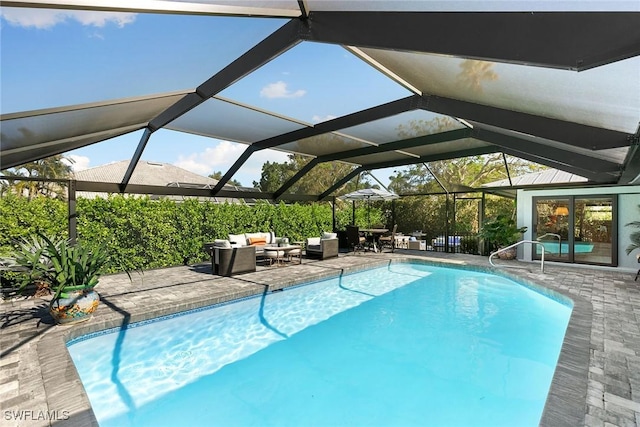 view of pool with outdoor lounge area, glass enclosure, and a patio