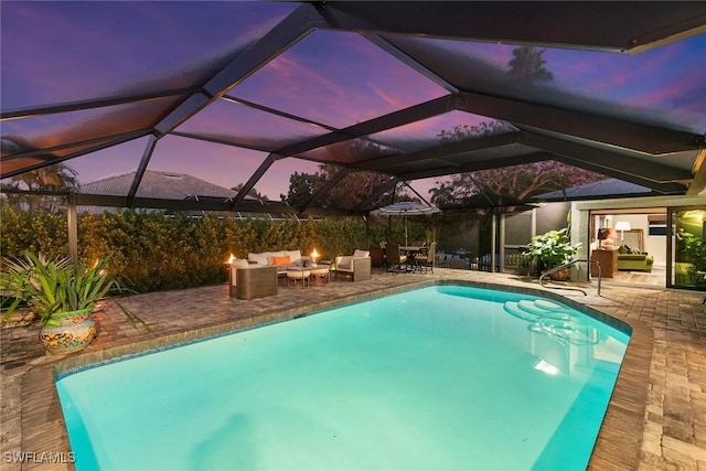 pool at dusk featuring a fire pit, a patio area, and a lanai