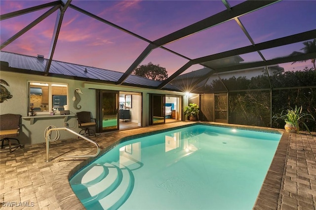 pool at dusk featuring a patio and glass enclosure