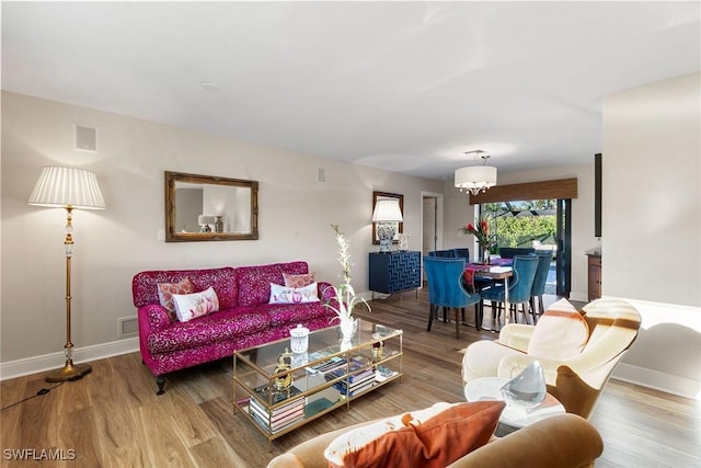 living room with an inviting chandelier and hardwood / wood-style flooring