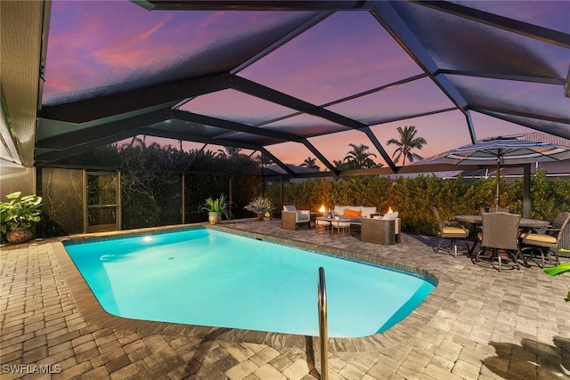 pool at dusk with a lanai, a patio area, and an outdoor living space with a fire pit