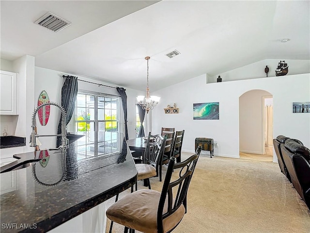 carpeted dining space featuring lofted ceiling and an inviting chandelier