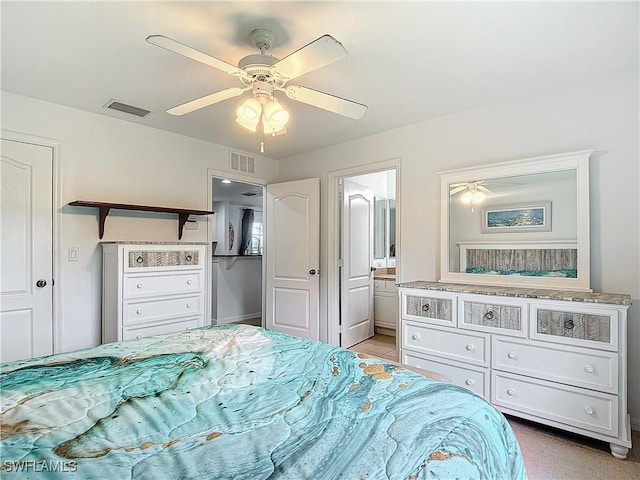 bedroom with ceiling fan, light colored carpet, and ensuite bathroom