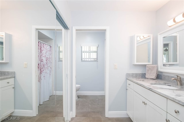 bathroom with tile patterned flooring, vanity, and toilet