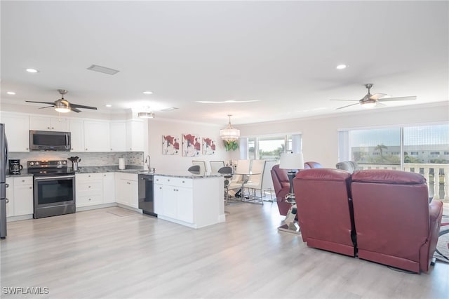 kitchen featuring hanging light fixtures, kitchen peninsula, decorative backsplash, white cabinets, and appliances with stainless steel finishes